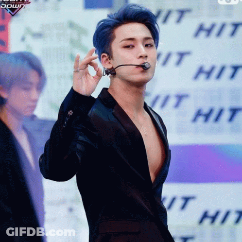 A Man With Blue Hair Is Wearing A Black Jacket And A Microphone GIF