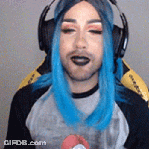A Man With Blue Hair Is Wearing Headphones And A Wig While Sitting In A Chair . GIF