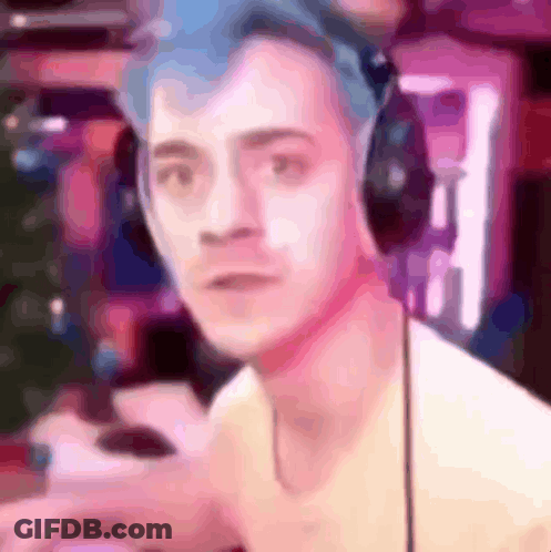 A Man With Blue Hair Is Wearing Headphones And Looking At The Camera In A Blurry Photo . GIF