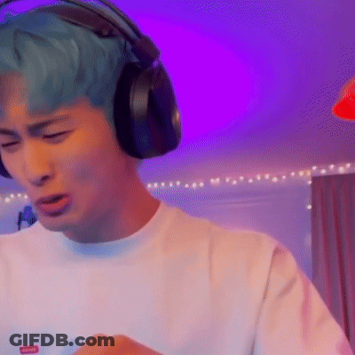 A Man With Blue Hair Is Wearing Headphones While Playing A Video Game . GIF