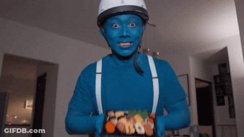 Man With Blue Face Paint And Suspenders Holding Food GIF