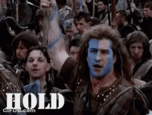 A Man With Blue Paint On His Face Is Standing In A Crowd . GIF