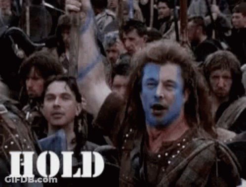 A Man With Blue Paint On His Face Is Surrounded By A Crowd Of People . GIF