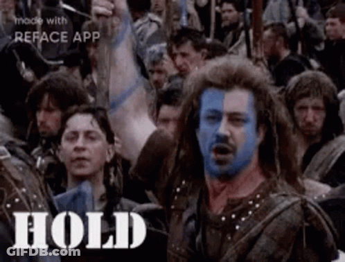 A Man With Blue Paint On His Face Is Surrounded By A Crowd Of People . GIF