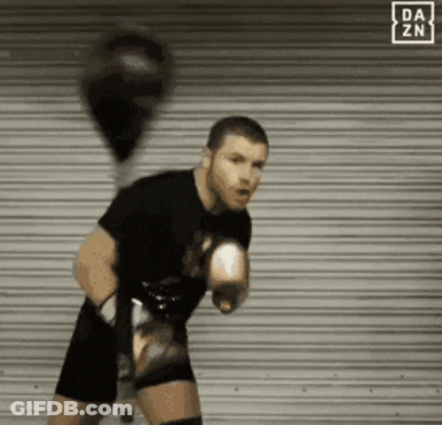 A Man With Boxing Gloves Is Standing In Front Of A Da Zn Sign GIF