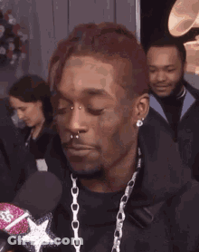 A Man With Braces On His Teeth Is Smiling While Holding A Microphone . GIF