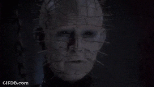 A Man With Chains Around His Neck Is Looking At The Camera GIF