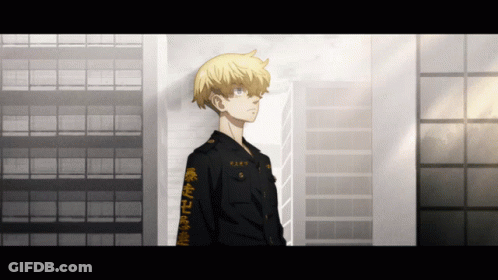 A Man With Chinese Writing On His Sleeve Stands In Front Of A Tall Building GIF