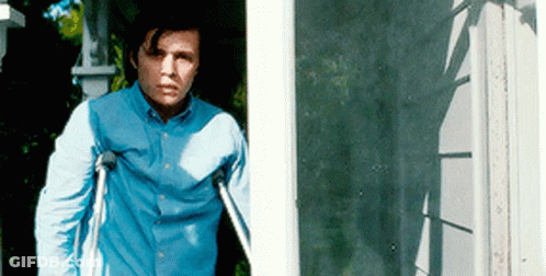 A Man With Crutches Is Standing In Front Of A Door GIF