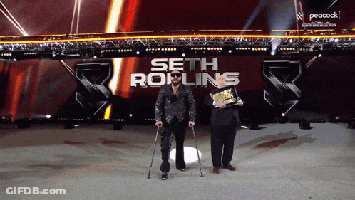 A Man With Crutches Stands In Front Of A Peacock Logo GIF
