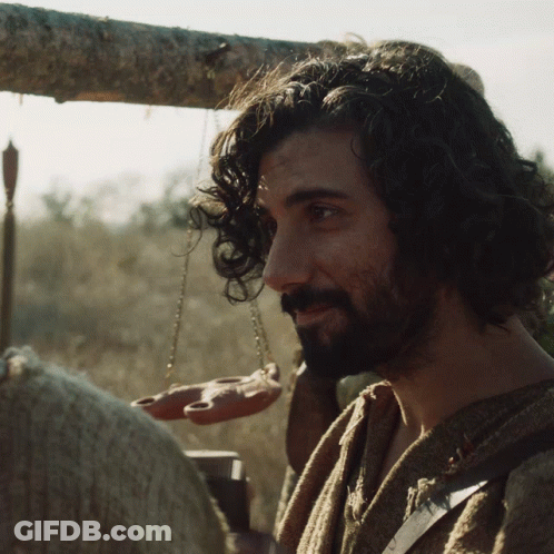 A Man With Curly Hair And A Beard Holds A Scale GIF