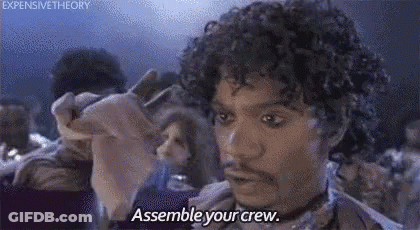 A Man With Curly Hair And A Beard Is Saying `` Assemble Your Crew '' While Holding A Piece Of Paper . GIF