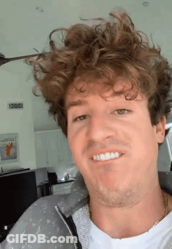 A Man With Curly Hair And A Beard Is Smiling GIF