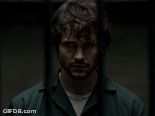A Man With Curly Hair And A Beard Is Standing In A Dark Room GIF