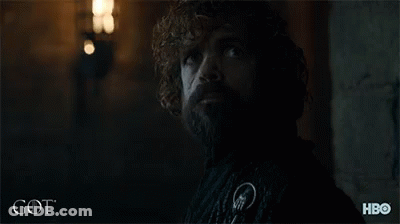 A Man With Curly Hair And A Beard Is Standing In A Dark Room With The Word Got On The Bottom Right GIF