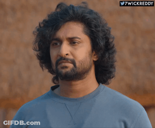 A Man With Curly Hair And A Beard Is Wearing A Blue Shirt With The Hashtag 7Wickreddy GIF
