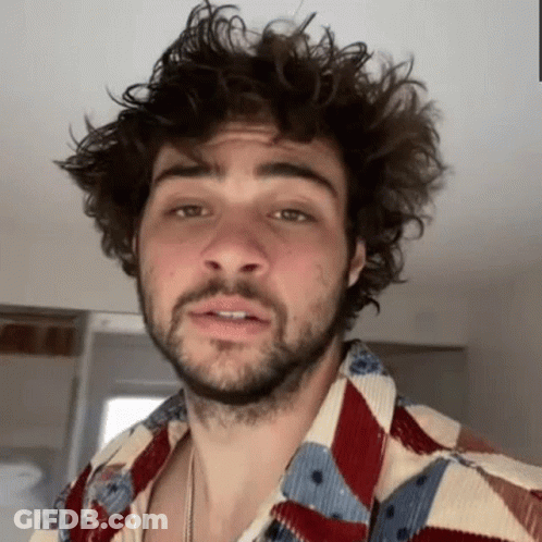 A Man With Curly Hair And A Beard Is Wearing A Colorful Shirt And Making A Funny Face . GIF