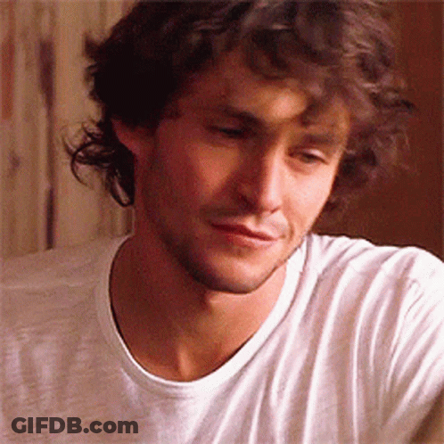 A Man With Curly Hair And A Beard Is Wearing A White Shirt GIF