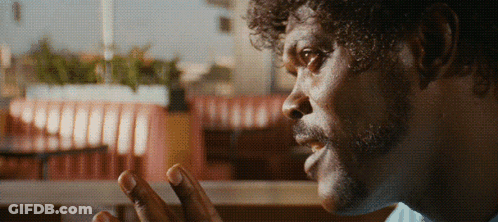 A Man With Curly Hair And A Beard Looks At Something GIF