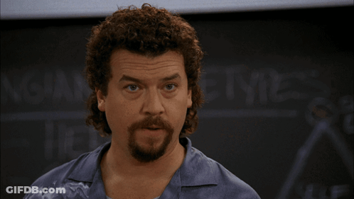 A Man With Curly Hair And A Beard Stands In Front Of A Blackboard That Says ' Ncaa ' On It GIF