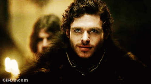 A Man With Curly Hair And A Fur Coat Is Looking At The Camera GIF