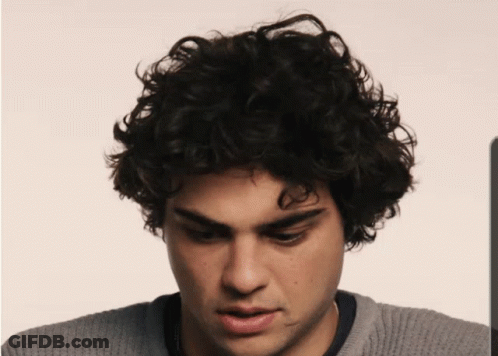 A Man With Curly Hair And A Gray Sweater GIF