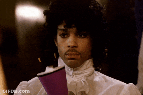 A Man With Curly Hair And A Mustache Holds A Purple Cup In His Hand GIF