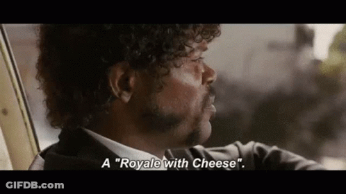 A Man With Curly Hair And A Mustache Is Sitting In A Car And Talking About A Royale With Cheese . GIF