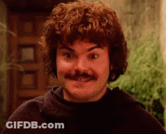 A Man With Curly Hair And A Mustache Is Smiling At The Camera . GIF