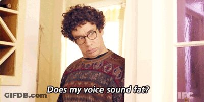 A Man With Curly Hair And Glasses Is Asking Does My Voice Sound Fat GIF