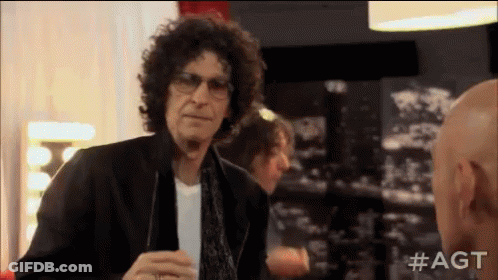A Man With Curly Hair And Glasses Is Talking To Another Bald Man . GIF