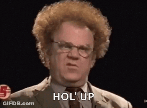 A Man With Curly Hair And Glasses Is Wearing A Suit And Tie And Saying Hol Up . GIF