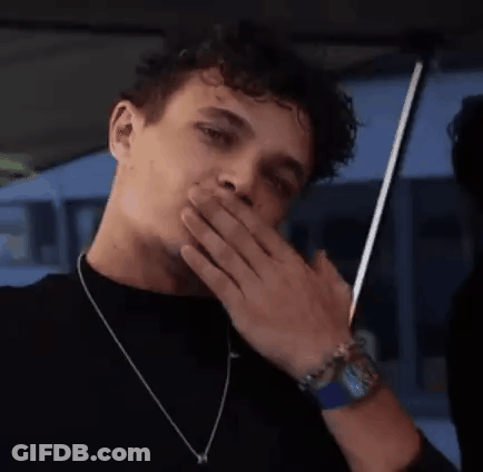 A Man With Curly Hair Is Covering His Mouth With His Hand . GIF