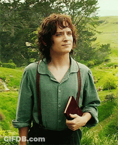 A Man With Curly Hair Is Holding A Book In A Field GIF