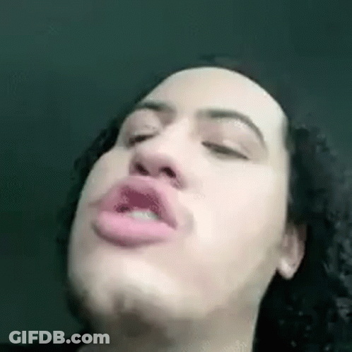 A Man With Curly Hair Is Making A Funny Face With His Eyes Closed And His Mouth Open . GIF