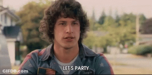 A Man With Curly Hair Is Saying `` Let 'S Party '' While Wearing A Denim Jacket . GIF