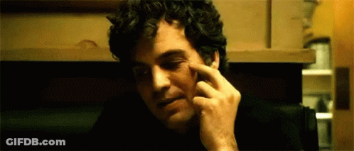 A Man With Curly Hair Is Scratching His Face With His Finger . GIF