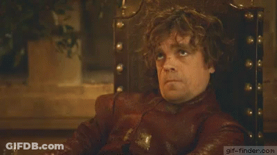 A Man With Curly Hair Is Sitting In A Chair And Making A Face . GIF