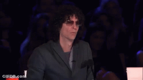 A Man With Curly Hair Is Sitting In Front Of A Microphone With His Mouth Open GIF