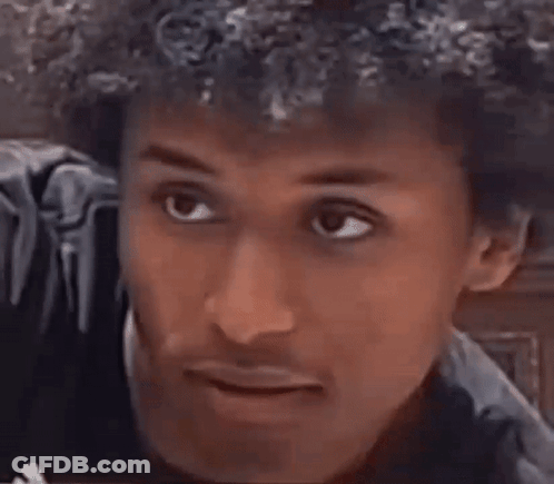 A Man With Curly Hair Is Smiling And Making A Funny Face With His Mouth Open . GIF