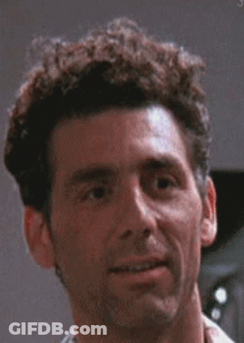 A Man With Curly Hair Is Smiling For The Camera . GIF