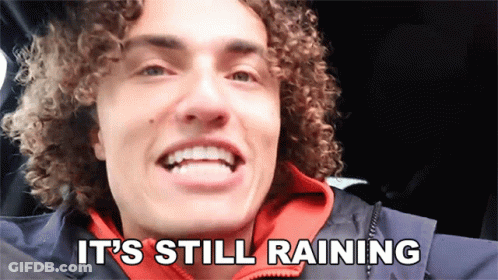 A Man With Curly Hair Is Smiling With The Words It 'S Still Raining Below Him GIF