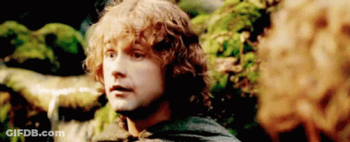 A Man With Curly Hair Is Standing In A Forest Looking At Another Man . GIF