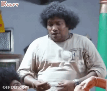 A Man With Curly Hair Is Standing In Front Of A Green Wall And Talking To Another Man . GIF