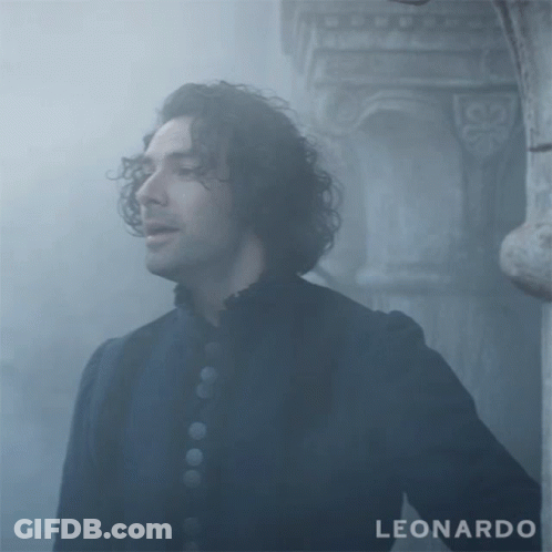 A Man With Curly Hair Is Standing In Front Of A Pillar With The Word Leonardo On The Bottom GIF