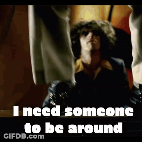 Curly-Haired Man In Front Of I Need Someone To Be Around Sign GIF