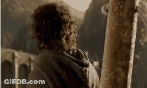 A Man With Curly Hair Is Standing In Front Of A Wooden Post . GIF