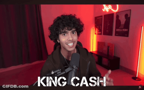 A Man With Curly Hair Is Talking Into A Microphone With The Words King Cash Written On The Bottom GIF