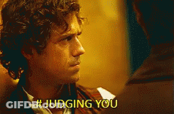 A Man With Curly Hair Is Talking To Another Man And Says # Judging You . GIF