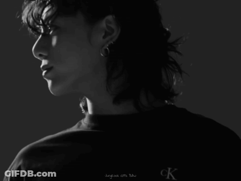 A Man With Curly Hair Is Wearing A Black Shirt That Says Calvin Klein Jeans GIF